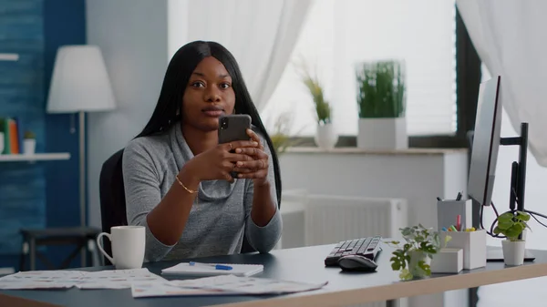 Estudiante negro sosteniendo el teléfono en las manos charlando con la gente buscando información de comunicación — Foto de Stock