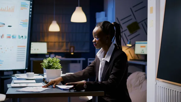 Businesswoman s tmavou pletí tvrdě pracující pozdě v noci v zasedací místnosti — Stock fotografie