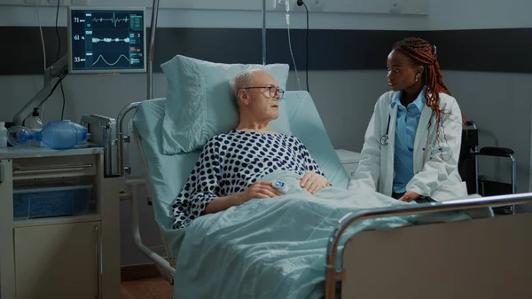 Afrikanisch-amerikanischer Arzt spricht mit kranken älteren Patienten — Stockfoto