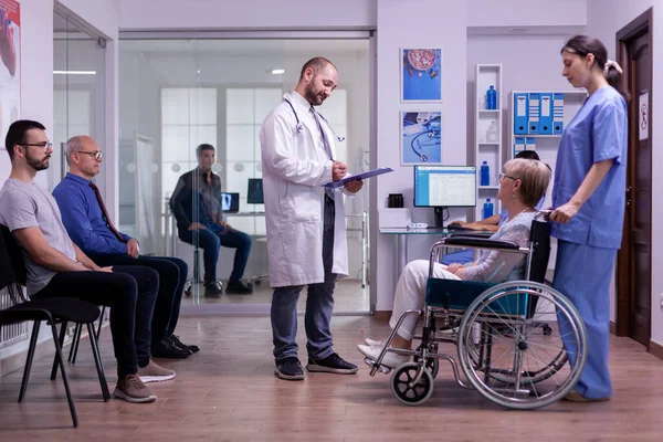 Facharzt überprüft Diagnose behinderter Seniorin im Rollstuhl — Stockfoto