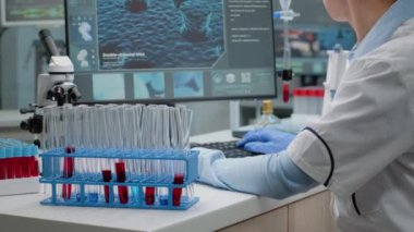 Test tüpü tutarken bilgisayar kullanan tıp bilimcisi