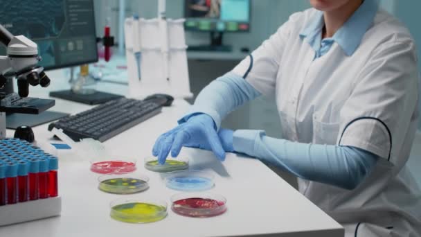 Científico en laboratorio analizando placa de Petri con bacterias líquidas — Vídeos de Stock