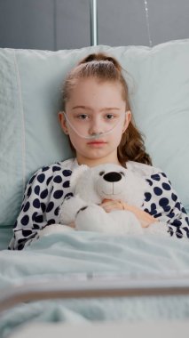 Küçük yalnız çocuğun portresi elinde oyuncak ayıyla kameraya bakıyor.