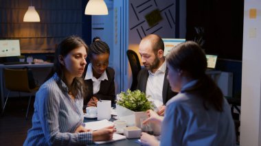 Konferans masasında oturan çok ırklı girişimciler, şirketin çözüm sunumunda fazla çalışıyorlar