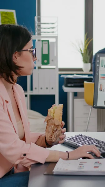 Geschäftsfrau isst leckeres Sandwich mit Essenspause bei der Arbeit im Unternehmen — Stockfoto