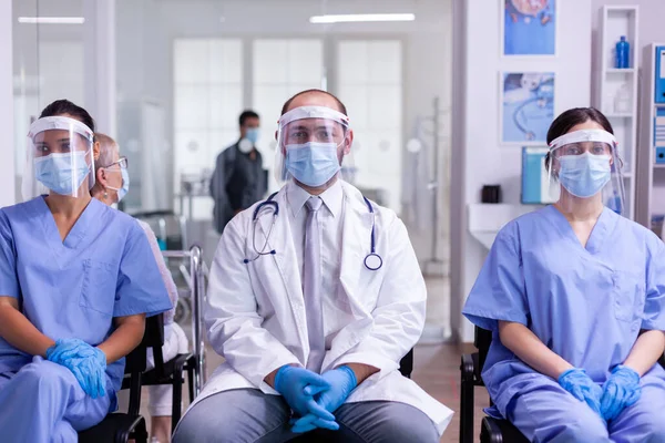 Grupo de pessoal médico olhando para a câmera usando máscara facial e viseira — Fotografia de Stock