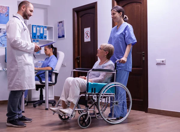 Specialist medic bespreken diagnose en herstel behandeling met gehandicapte senior — Stockfoto
