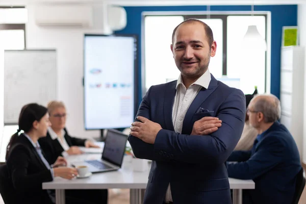 Joven empresario sonriendo delante de la cámara de pie en la sala de lluvia de ideas — Foto de Stock