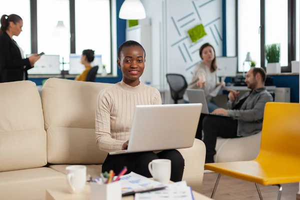 African woman manager sitting on couch in front of camera smiling — Stock Photo, Image