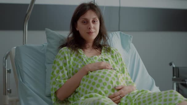 Portrait of adult with pregnancy holding belly in hospital ward — Stock Video