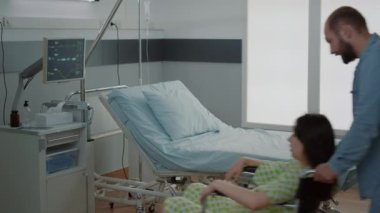 Genç baba tekerlekli sandalyedeki hamile eşi destekliyor.