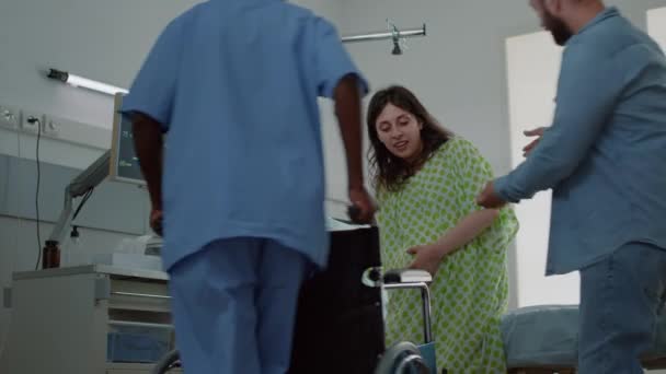 Kaukasischer Mann hilft schwangerer Frau auf Krankenhausstation — Stockvideo