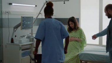 Koca ve Afrikalı Amerikalı hemşire hamile karısına yardım ediyor.