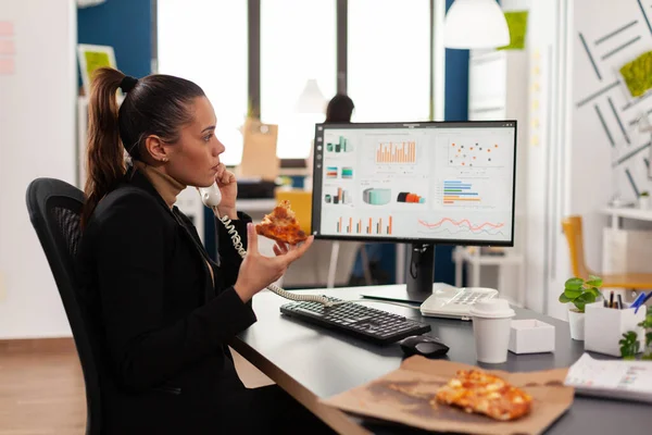 Closeup van zakenvrouw zitten aan het bureau in de voorkant van computer eten pizza slice — Stockfoto