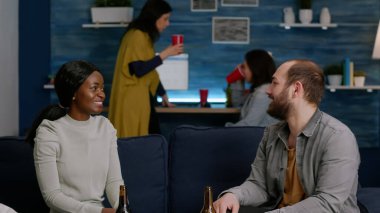 Erkek arkadaşıyla beşlik çakarken Afro-Amerikalı kadın kanepede dinleniyor.