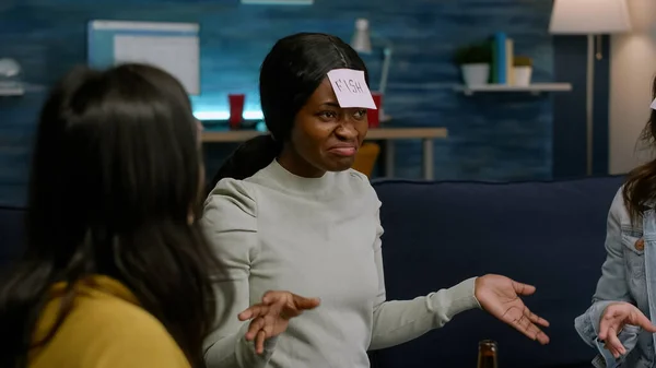 Excited multiethnic friends with sticky notes on foreheads playing guess who game — Stock Photo, Image