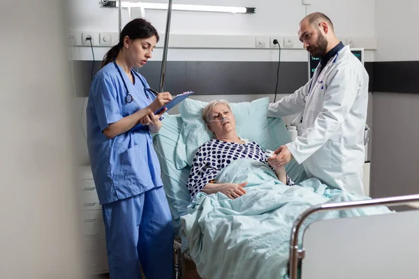 Νοσοκόμα κρατά σημειώσεις στο πρόχειρο κατά τη διάρκεια της διαβούλευσης των ηλικιωμένων γυναικών — Φωτογραφία Αρχείου