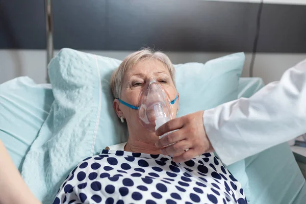 Médecin et infirmière supervisant une femme âgée respirant avec un masque à oxygène — Photo