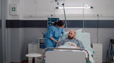 Kadın pratisyen asistanı kalp atışlarını izleyen hasta adamı kontrol ediyor.