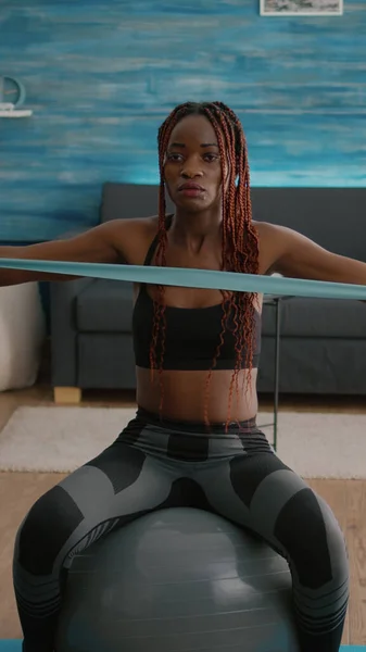 Ajuste mujer negra haciendo ejercicios de yoga usando bandas elásticas en bola suiza — Foto de Stock