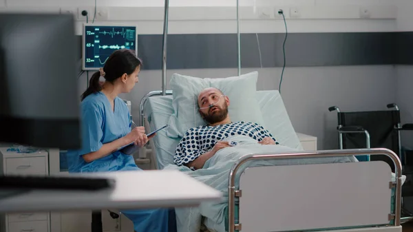 Homem doente sentado na cama com tubo de oxigênio explicando sintoma de doença para enfermeira médica — Fotografia de Stock