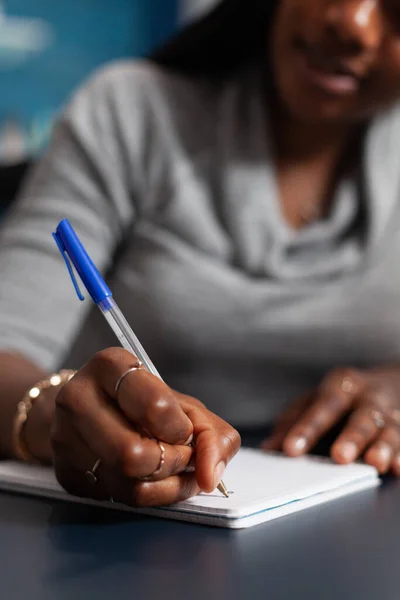 Closeup of black student hands writing university homework during online communication lesson — Stockfoto