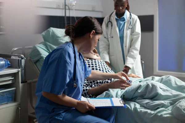 Medische assistent controleert oximeter bevestigd aan senior man — Stockfoto