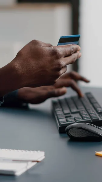 Primo piano di afro-americano uomo mani digitando informazioni sulla carta di credito sul keyborad del computer — Foto Stock