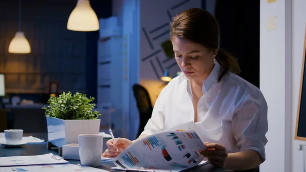 Overwerkte zakenvrouw schrijven van financiële winst op notebook tijdens het werken in het bedrijfsleven vergadering — Stockfoto