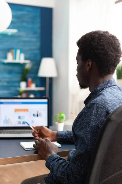 Homem negro trabalhando em casa usando o aplicativo de dados de economia financeira — Fotografia de Stock