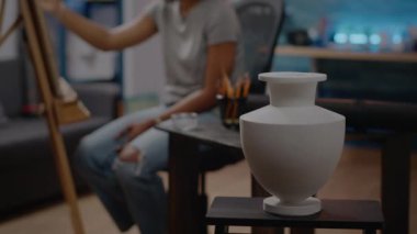 Evdeki resim stüdyosunun masasındaki beyaz vazoyu kapat.