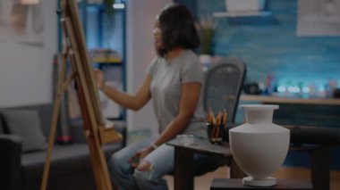 Masada beyaz vazo kullanan Afrikalı Amerikalı kadın.