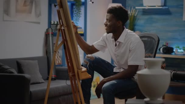 Schwarzer junger Erwachsener sitzt im Kunstatelier und zeichnet Vase — Stockvideo