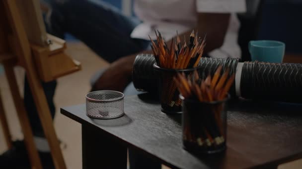 Крупним планом чорна рука використовує барвисті олівці на столі — стокове відео
