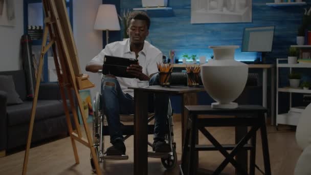 Afro-Amerikaanse man met een handicap met behulp van digitale tablet — Stockvideo