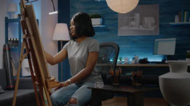 Atölyede oturan zenci sanatçı kadın.