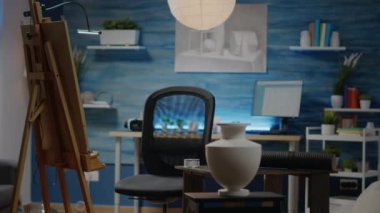 Beyaz vazo ve çizimlerle dolu boş bir sanat stüdyosu odası.