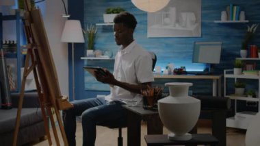 Vazo tasarımı için tablet kullanan sanatsal yetenekleri olan siyah bir adam.