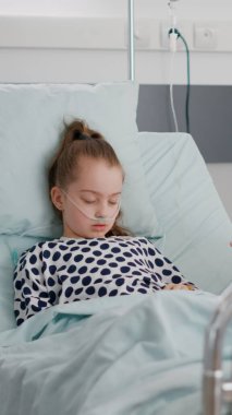 Endişeli anne, hasta ameliyatından sonra kızının yanında oturmuş dua ediyor.