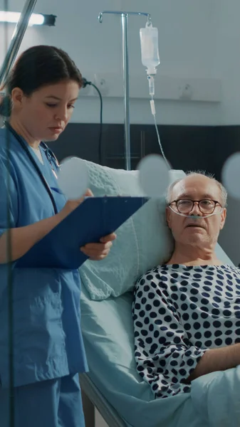Infermiera caucasica che controlla il paziente anziano nel reparto ospedaliero — Foto Stock