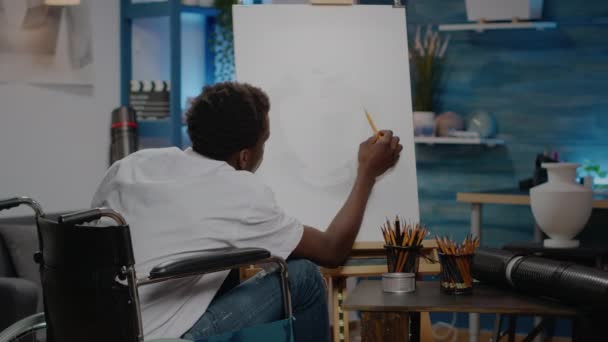 Sanatsal alanda oturan siyah sakat kişi vazo çiziyor — Stok video