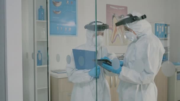 Estomatólogos que usan trajes de materiales peligrosos con tabletas para la higiene dental — Vídeo de stock