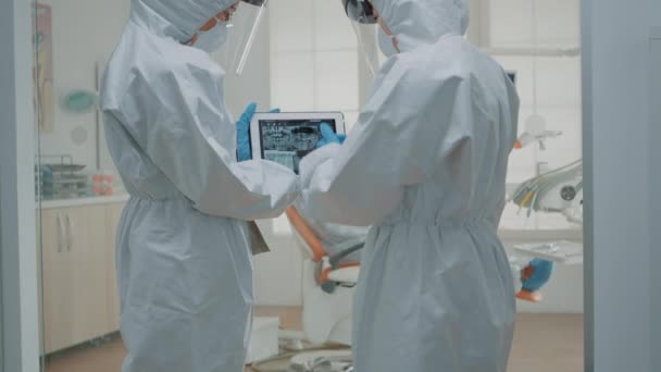 Team av tandläkare bär ppe kostymer medan du tittar på röntgen — Stockvideo