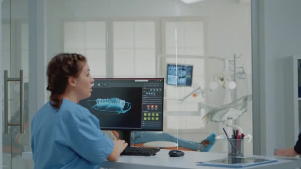 Assistante en dentisterie utilisant un ordinateur avec animation dentaire virtuelle — Video
