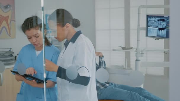 Dentista y asistente analizando la pantalla de tableta moderna — Vídeos de Stock
