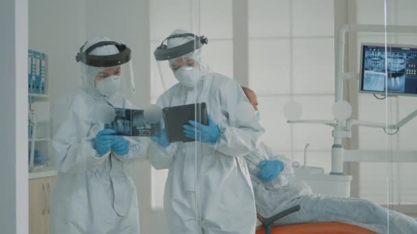 Tandarts en assistent die röntgenfoto 's en tabletten onderzoeken in de mondkliniek — Stockvideo