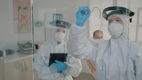 口腔科医生小组穿着ppe西服，用平板电脑 — 图库视频影像