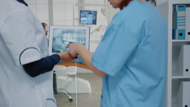 Dentysta i pielęgniarka analizujący radiografię zębów w tabletce — Wideo stockowe