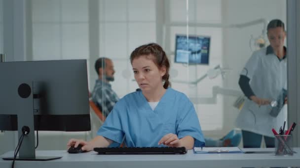 Tandläkare med hjälp av dator och röntgen skannar vid skrivbordet — Stockvideo