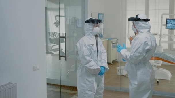 Médecins stomatologiques portant des combinaisons ppe à la clinique dentaire — Video